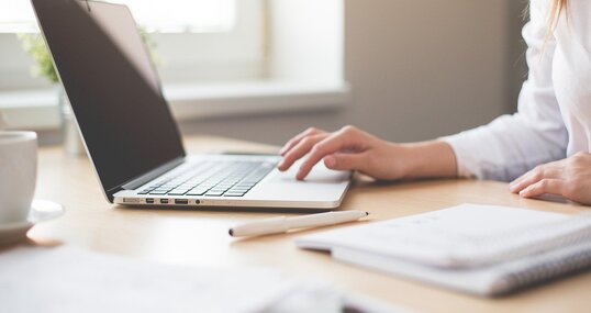 Notebook mit Frauenhand und Block