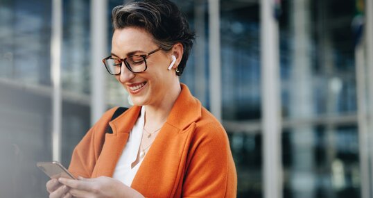 Smiling businesswoman reading a text message on her phone while commuting to her office in the city