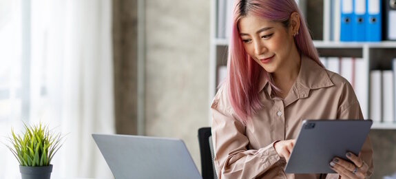 Portrait of a young Asian businesswoman working on a tablet with a laptop at the thinking office. analyze marketing data online business ideas.