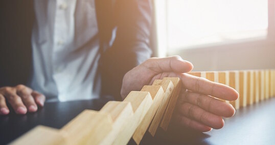 Problem Solving,Close up view on hand of business woman stopping falling blocks on table for concept about taking responsibility.