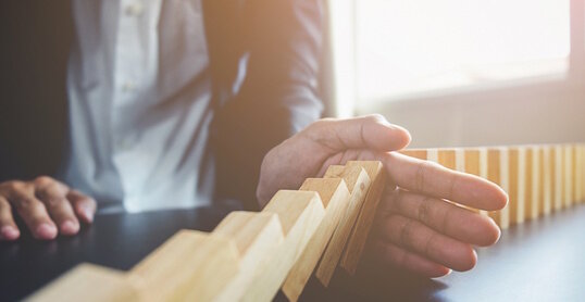 Problem Solving,Close up view on hand of business woman stopping falling blocks on table for concept about taking responsibility.