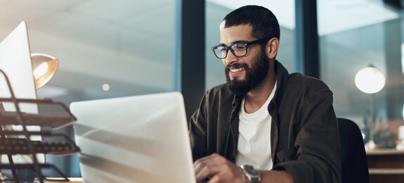 Smile, work and a businessman with a laptop for an email, communication or online coding. Happy, programming and a male programmer typing on a computer for web or software development in an office