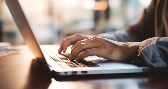 Close up of a business man working on a laptop, typing with his hands for work in office environment home office