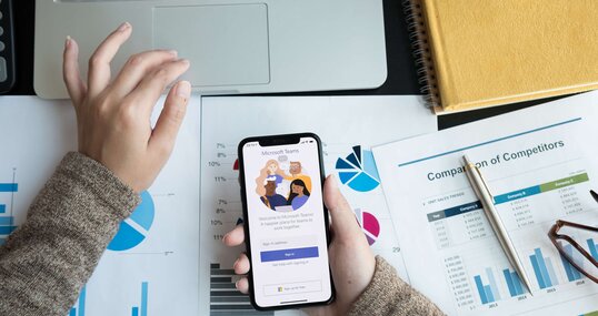 Eine Angestellte lädt auf ihrem Handy die Microsoft Teams App für digitale Zusammenarbeit herunter.