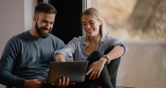 Young happy couple. Boyfriend and girlfriend using laptop together.