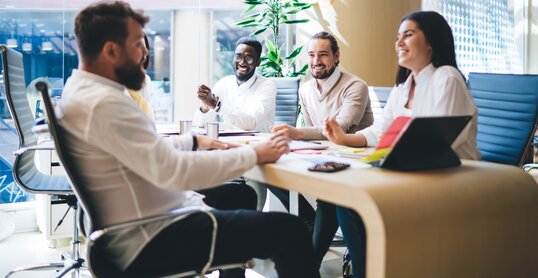 Cheerful diverse colleagues gathering on meeting in office