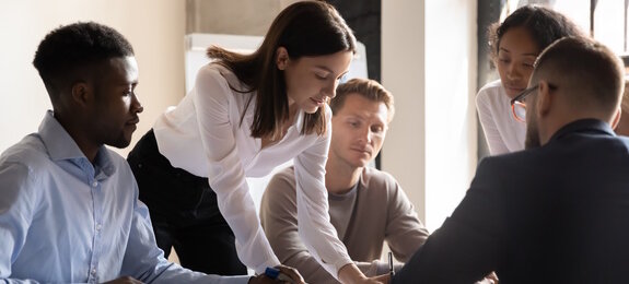 Diverse colleagues working on project together, sitting at table in boardroom, working with legal documents, financial report with statistics, employees engaged in teamwork at corporate meeting