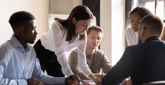 Diverse colleagues working on project together, sitting at table in boardroom, working with legal documents, financial report with statistics, employees engaged in teamwork at corporate meeting