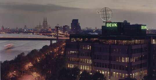 Foto der Firmenzentrale der DEVK mit Kölner Skyline im Hintergrund im Abendlicht