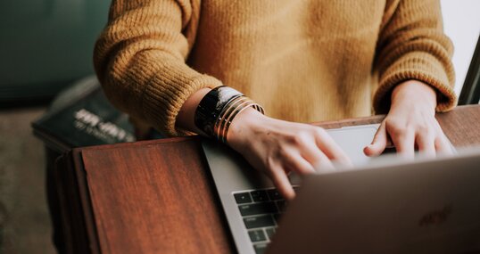 Frau im Pullover arbeitet am Laptop