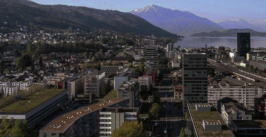 Ein Panorama der Stadt Zug mit See und Bergen im Hintergrund.