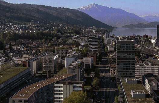 Ein Panorama der Stadt Zug mit See und Bergen im Hintergrund.