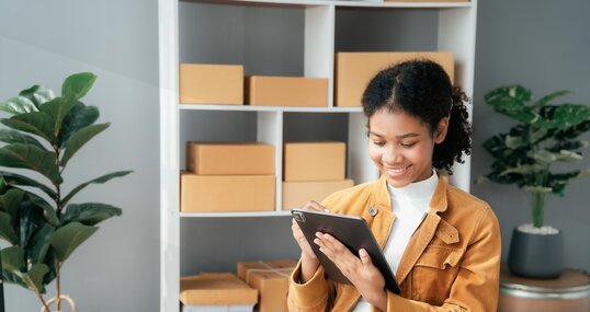 Junge Frau sitzt am Schreibtisch und arbeitet am Tablet