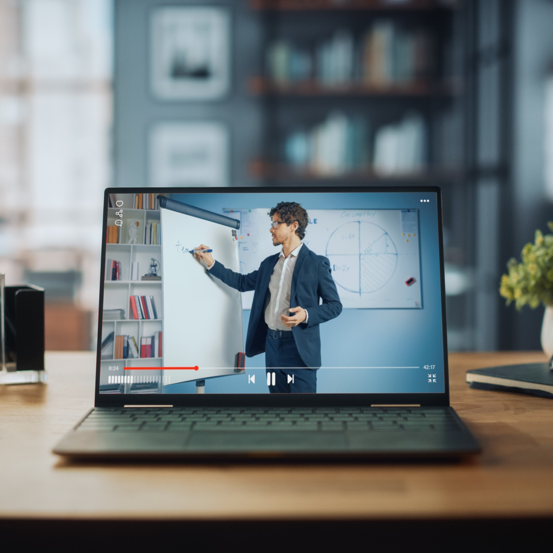Shot of a Laptop Computer Showing Online Lecture with Portrait of a Cute Male Teacher Explaining Math Formulas. It is Standing on the Wooden Desk in Stylish Modern Home Office Studio During Day.
